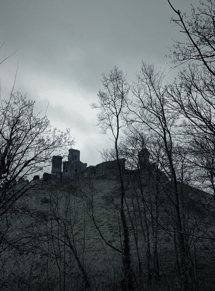 Corfe Castle on a cloudy, rainy day in January. English castle ruins. Gothic style photograph effect.