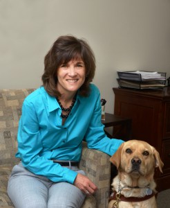 Becky is seated with her guide dog Georgie by her side