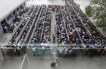 Passengers, seen through glass, line up and wait for a security check during morning rush hour at Tiantongyuan North Station in Beijing May 27, 2014. Beijing tightened security checks at subway stations since last Saturday, following an attack in China's troubled Xinjiang region which killed 31 people on May 22, the deadliest act of violence in the region in years. REUTERS/Jason Lee (CHINA - Tags: TRANSPORT CRIME LAW CIVIL UNREST)